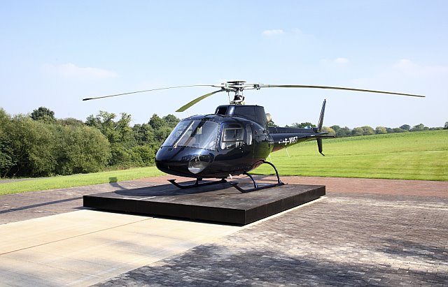 Helicopter parked outside its purpose-built prefabricated steel aircraft hangar.