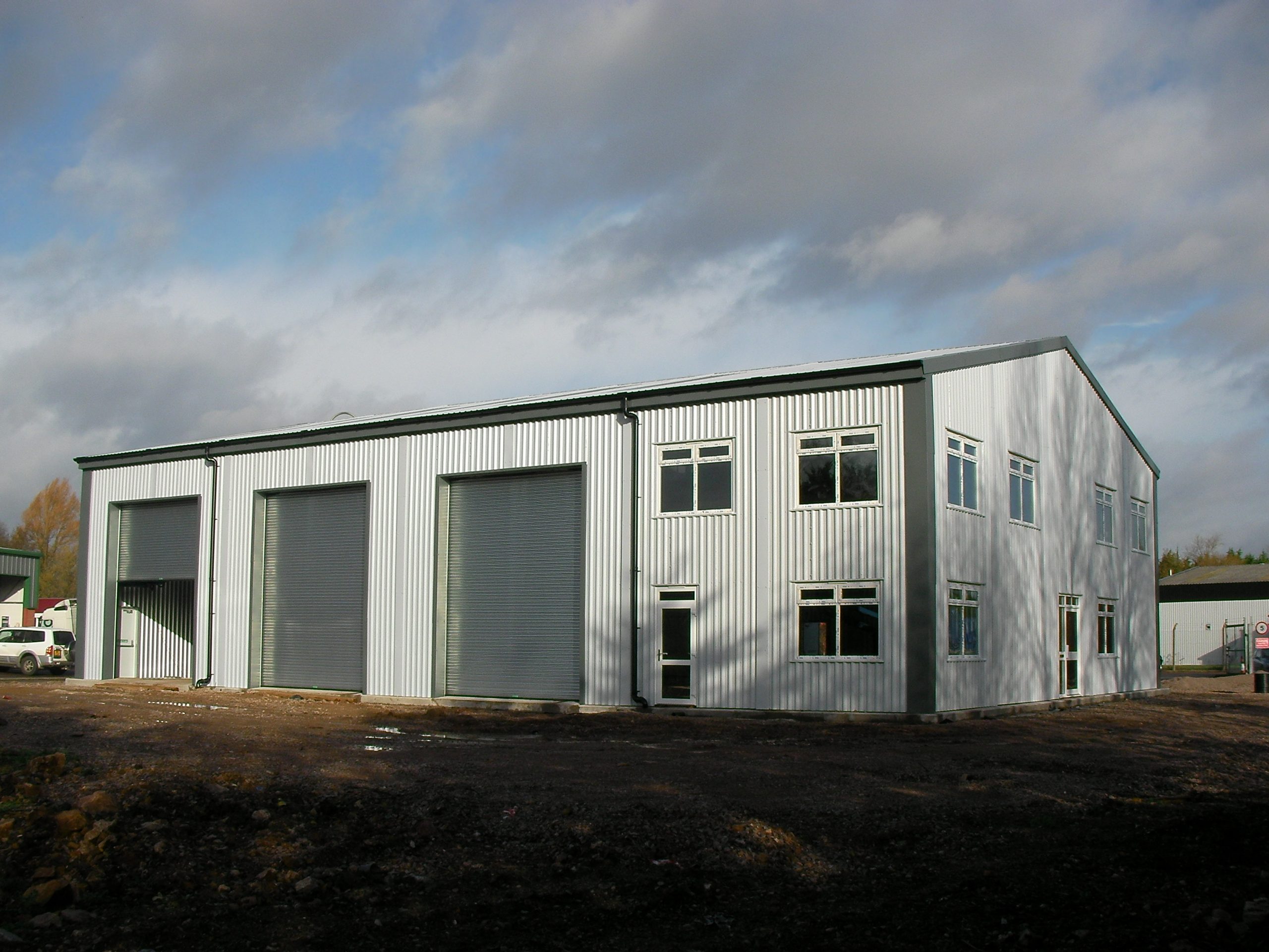 Prefabricated steel high bay warehouse and storage building for James Bevan, with roller shutter doors and two-storey offices.