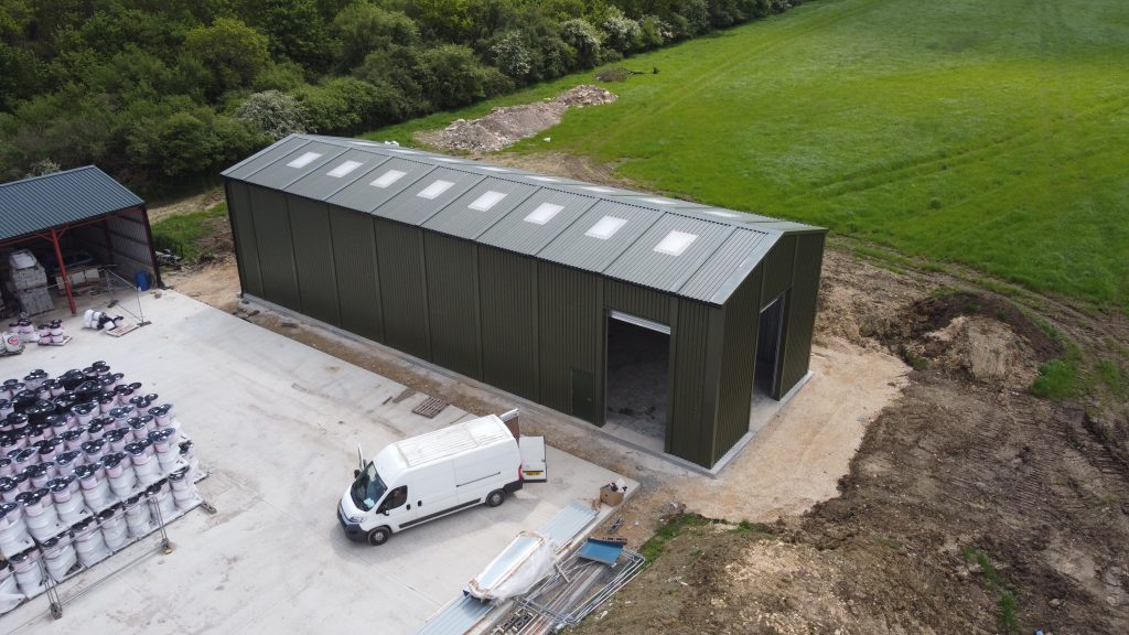Aerial view of a relocatable steel storage building for Utranazz, featuring dark green cladding, rooflights and roller shutter access doors.